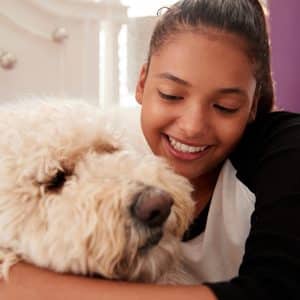 young-teen-girl-embracing-pet-dog-on-her-bed-PGQHKBW.jpg